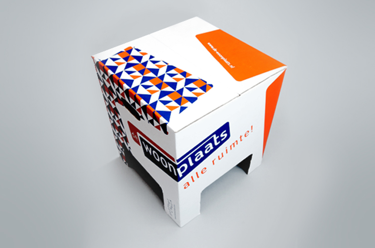 Kartonnen krukje met de kleurelementen en het logo van De Woonplaats