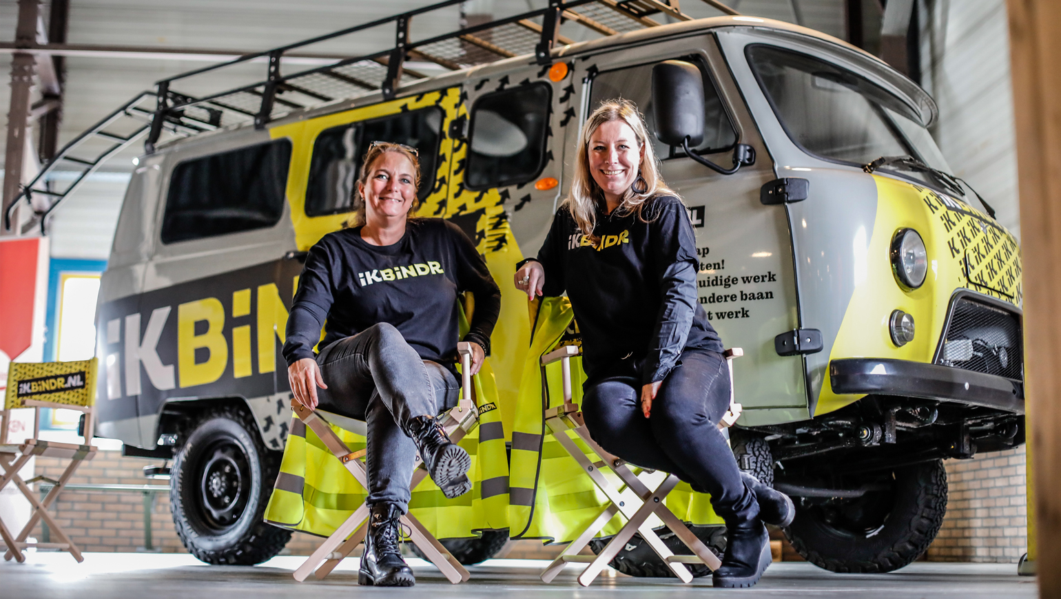 Twee vrouwen op een stoel met daarachter het busje van IKBINDR