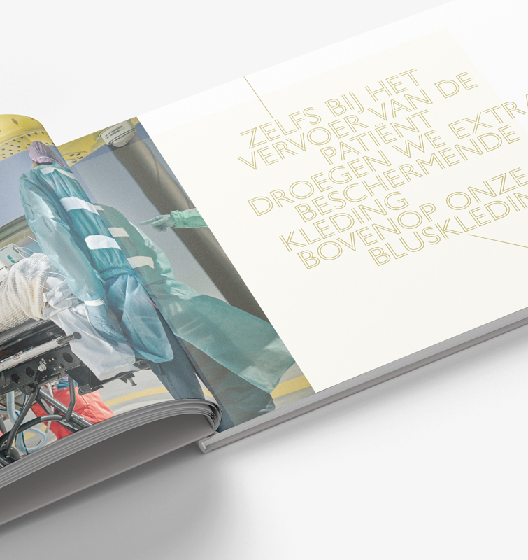 Opengevouwen boek met een foto van een medewerker die een patiënt op de brancard in de ambulance laadt