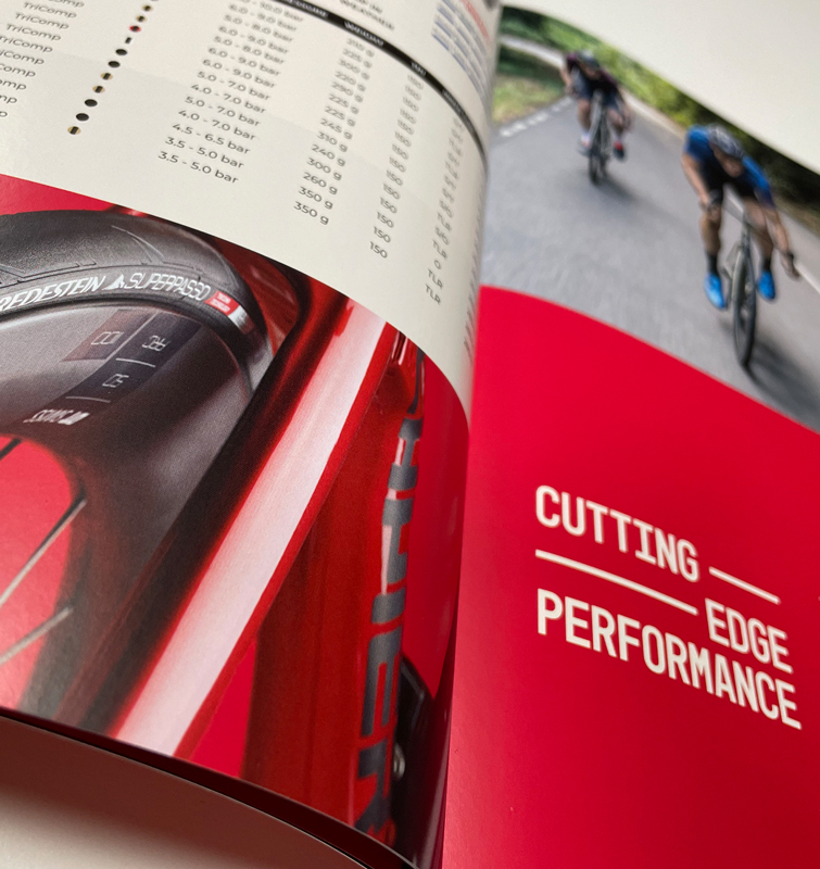 Opengeslagen catalogus ingezoomd op een afbeelding van een rode fiets met een Vredestein band