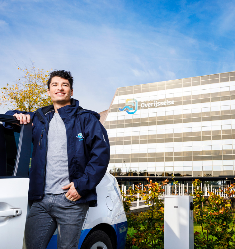 Man staat naast auto voor het gebouw van Drents Overijsselse Delta